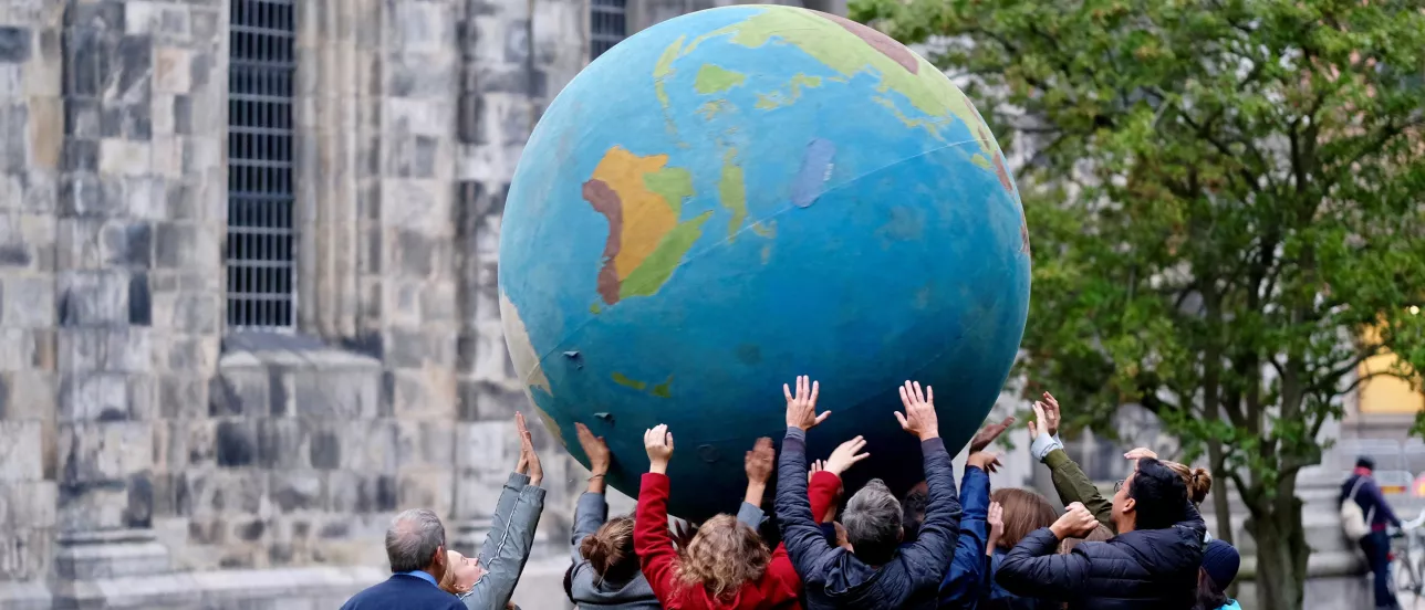 Lots of people holding up a big globe in front of the cathedral in Lund