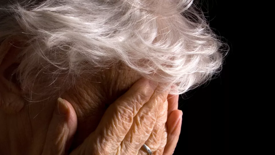 Elderly woman with head in hands