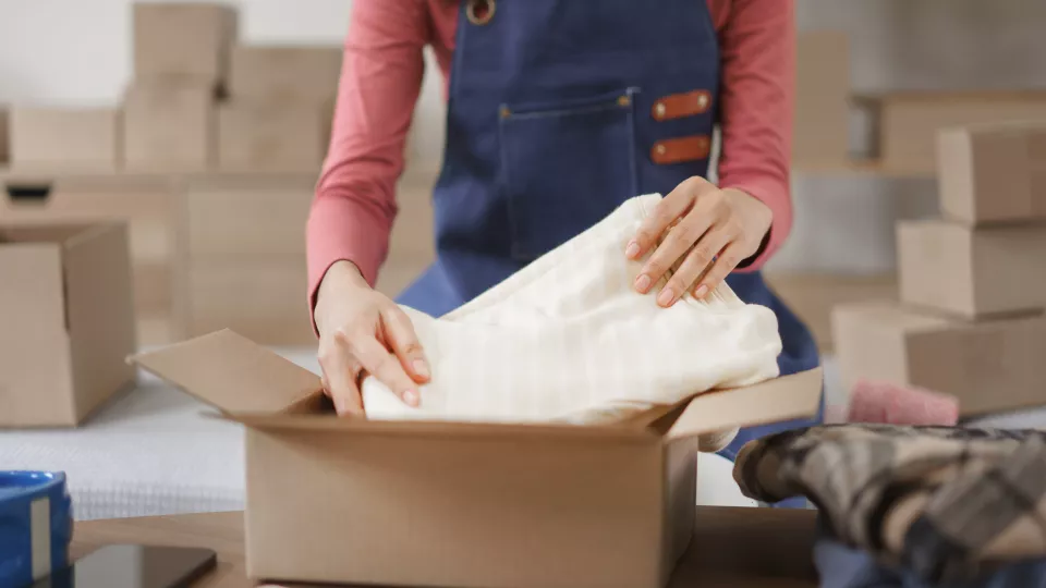 Woman packing clothing into box