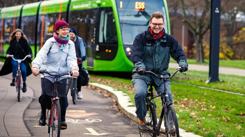 Four students biking and laughing with a tram in the background. Photo: Johan Persson.