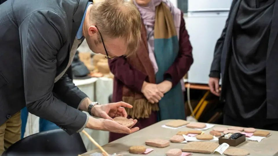 Researchers bending over replicas of the clay tablets
