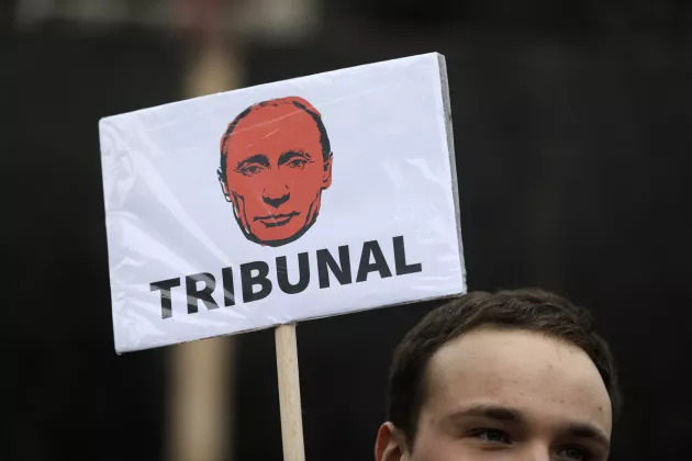 Demonstrator holds a placard depicting Russian President Vladimir Putin with the text "tribunal". Photo: Andrej Cukic/EPA.