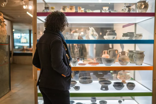 Person looking at old pottery. Photo.