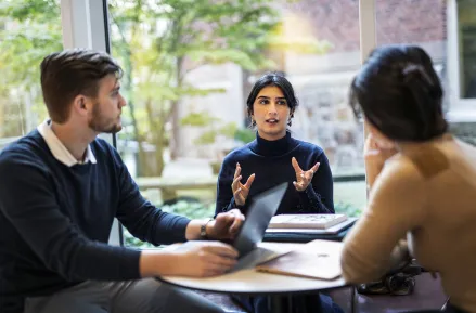 A person gestures while explaining something to two others. Photo: Johan Persson.