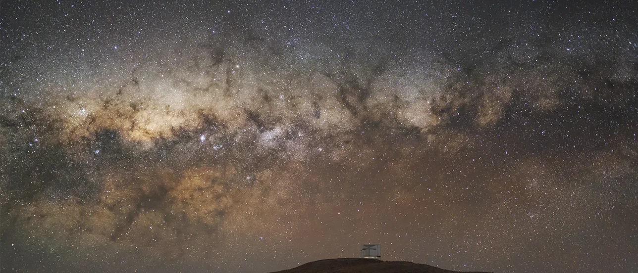 The Great Rift sweeps across the sky above ESO’s Paranal Observatory, hiding the Milky Way’s glow. With infrared eyes, the VISTA telescope reveals the galaxy’s secret heart. Photo: ESO/M. Zamani.