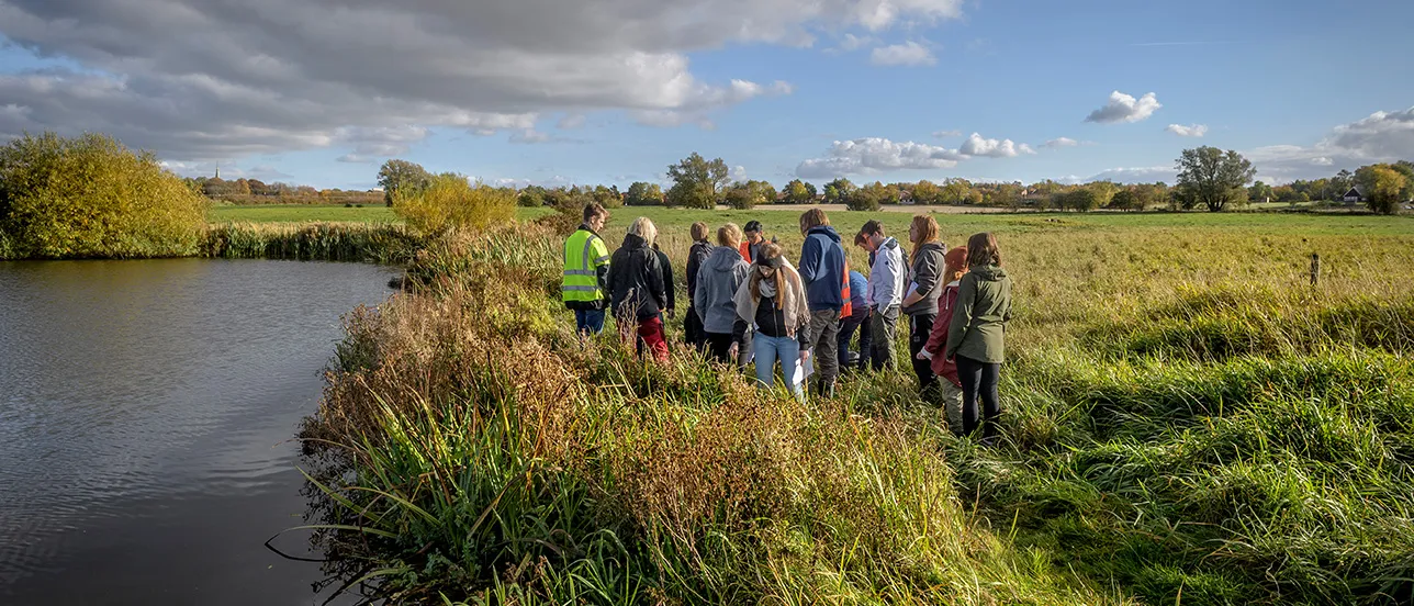 Photo. A group of students on a field trip next to a lake.