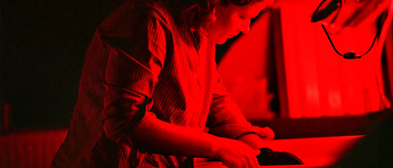 Female student developing photographs in a darkroom. Photo.
