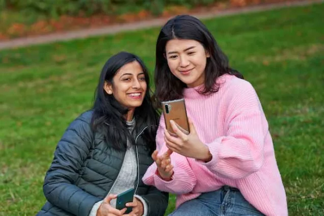 Two students looking at their phones. Photo.