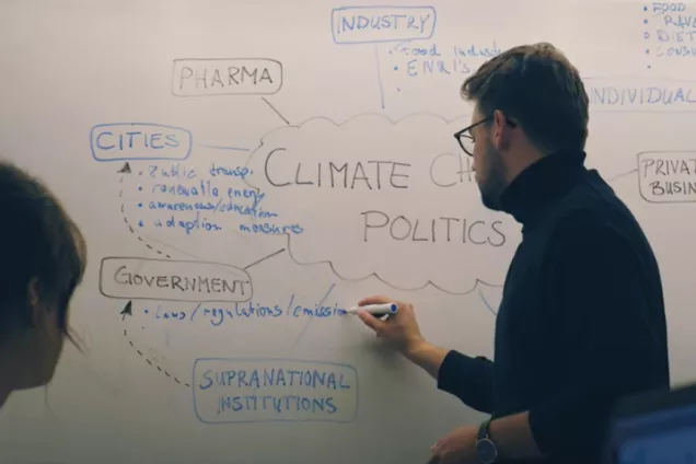 A student writing about climate-related matters on a whiteboard. Photo.