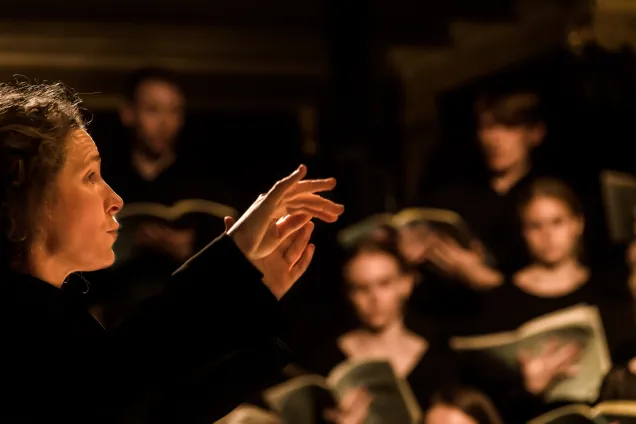 Conductor leads choir. Represents the benefits available to members of the alumni network. Photo. 