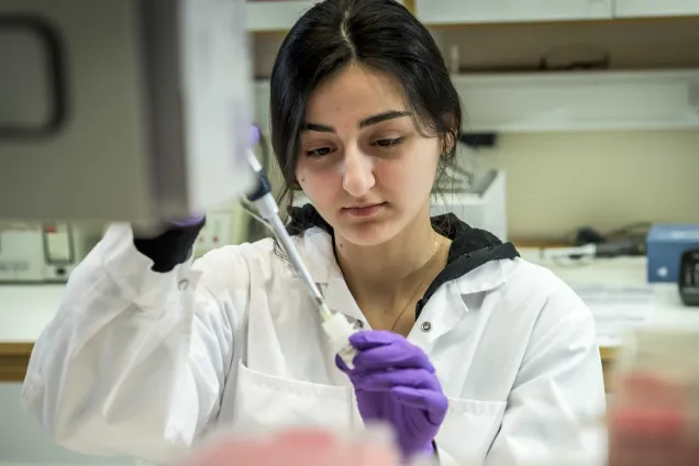 Person in a lab using a pipette.