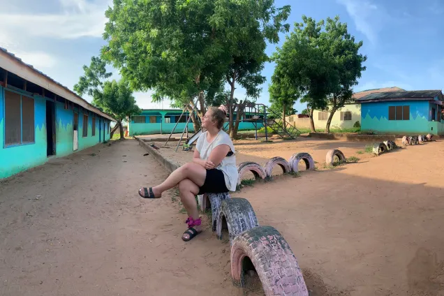 Student sitting on a fence made of decks. Photo.