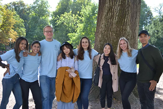 new international students and mentors posing together in front of a tree