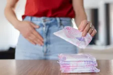A young woman stands infront of a pile of sanitary products. Photo: iStock