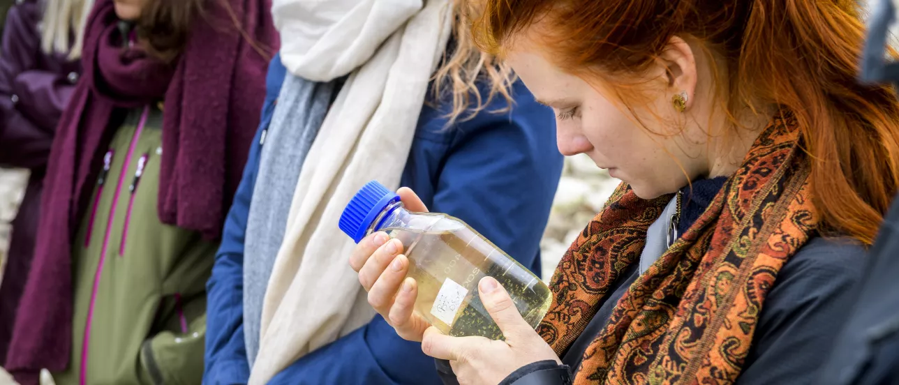 A student looking at a bottle with water during an excursion