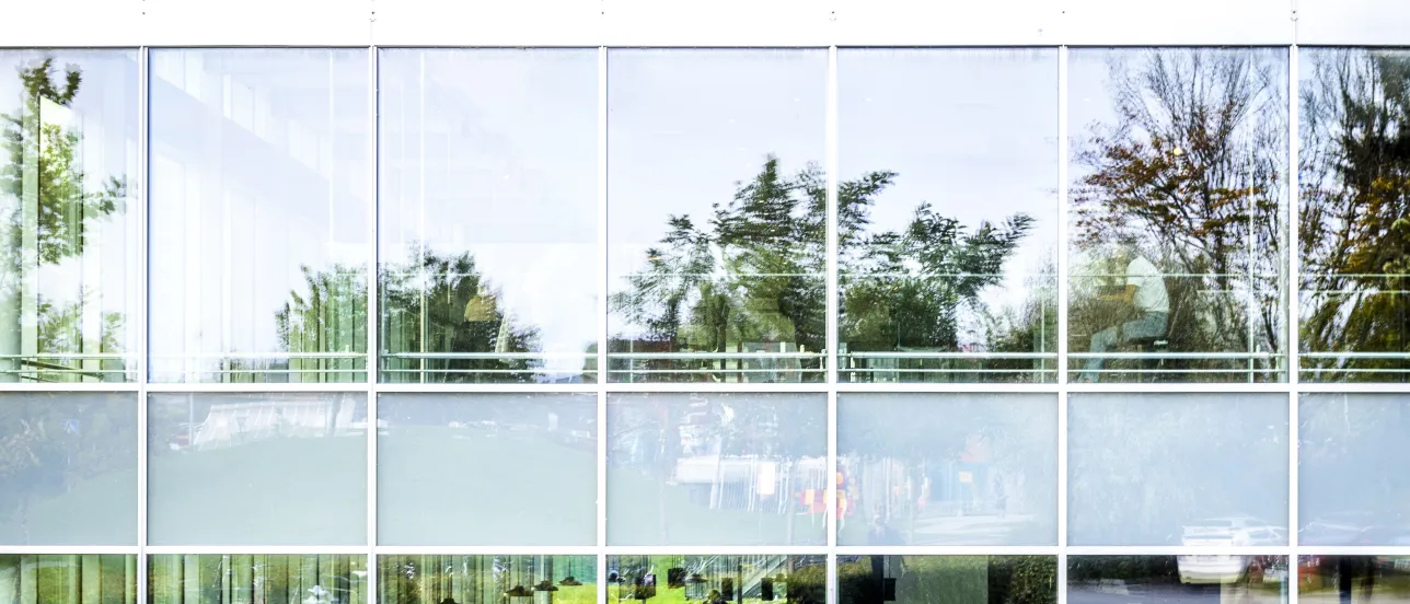 People are sitting and studying in a building with large glass windows.