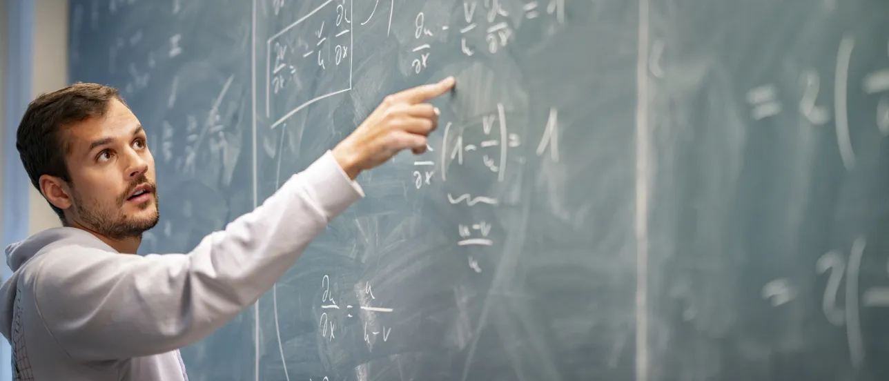 Teacher points on a calculation on a board.