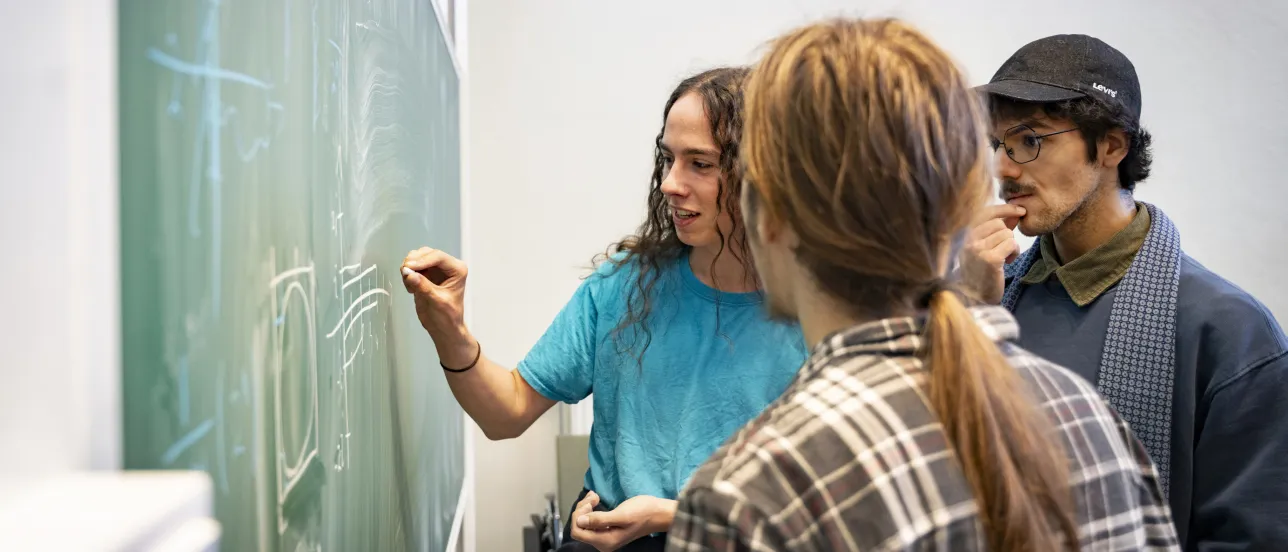 Students discussing a calculation at the blackboard.