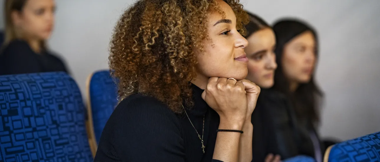 Female student in focus sitting in an auditorium listening to lecture. Photo