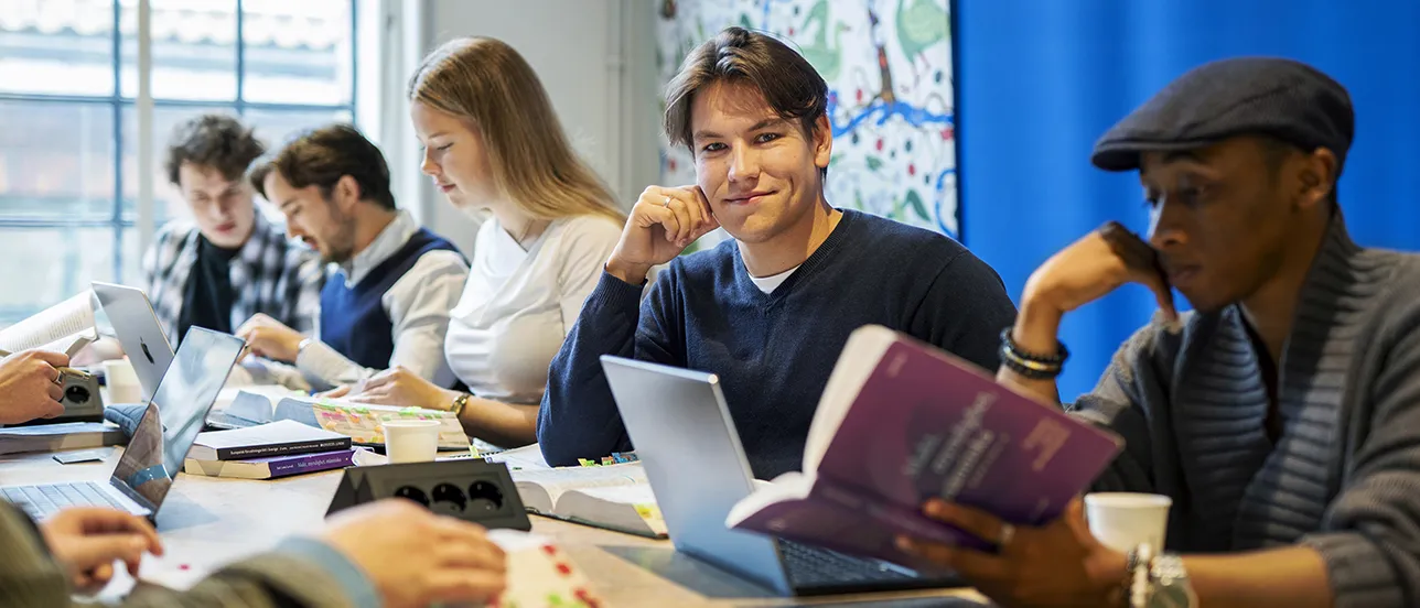 Students studying law texts, one student is looking in to the camera. Photo.