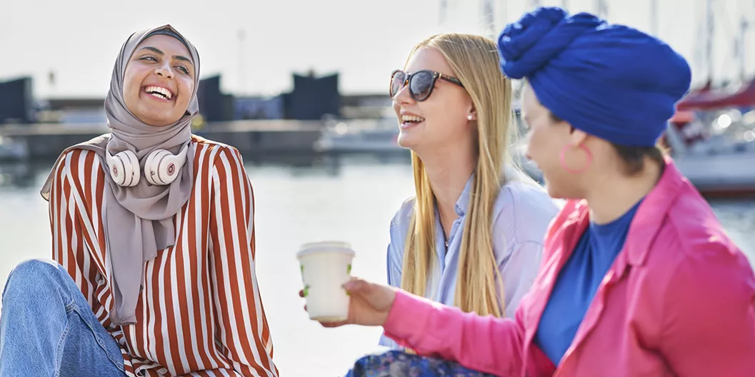 Three students talking and laughing at the harbour in Helsingborg in summertime.
