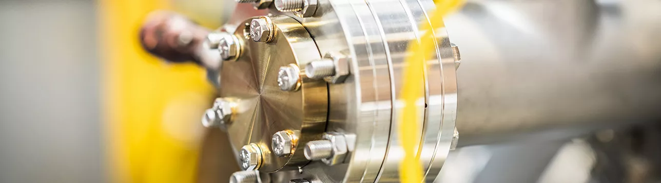 A close-up of a industrial vacuum chamber with numerous connectors and cables, set in a blurred technological environment. Photo.