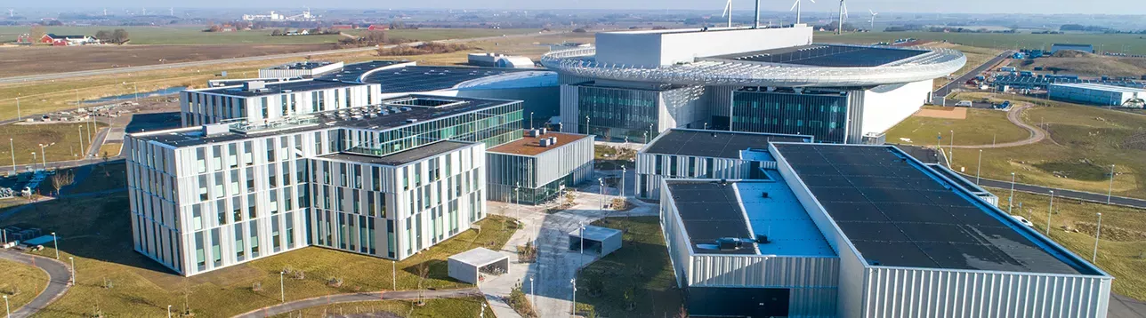 Aerial view of the modern scientific complex with a circular building and connected rectangular structures in an open landscape. Roger Eriksson/ESS. Photo.