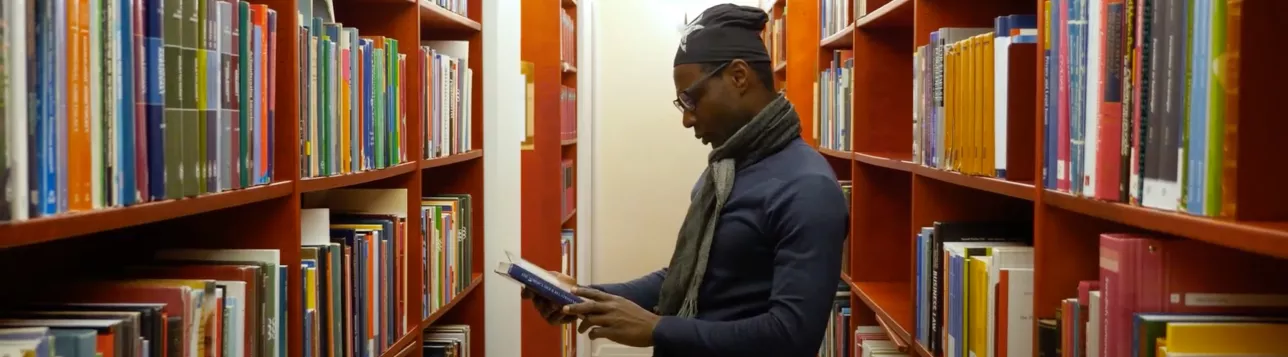A student surrounded by books in the Faculty of Law library. Screenshot.
