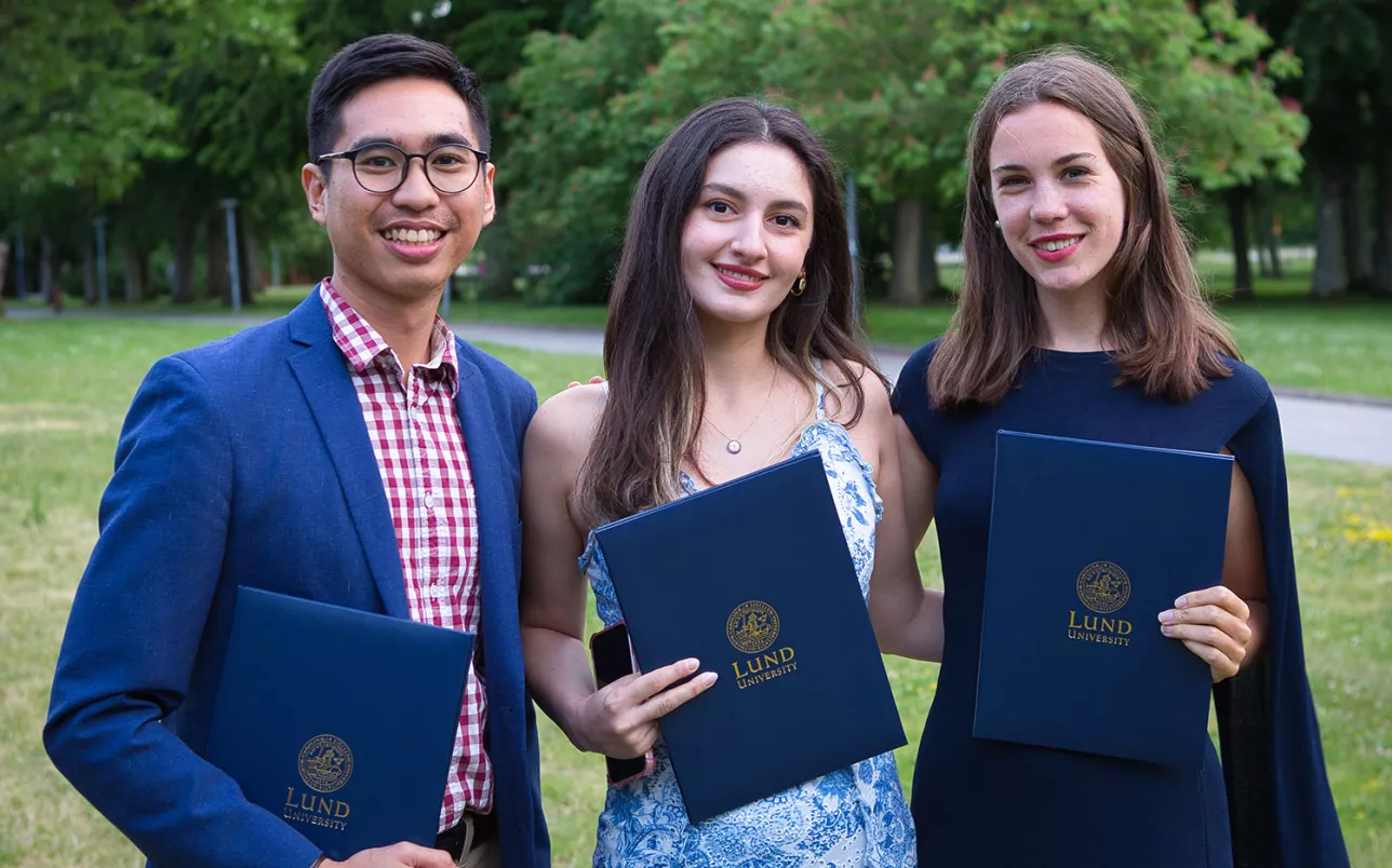 Three students holding diplomas from Lund University. Photo.