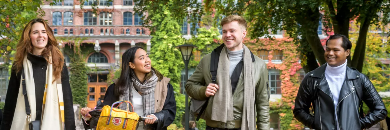 Four students walking in front of the Main University Library in autumn. Photo: Kennet Ruona.