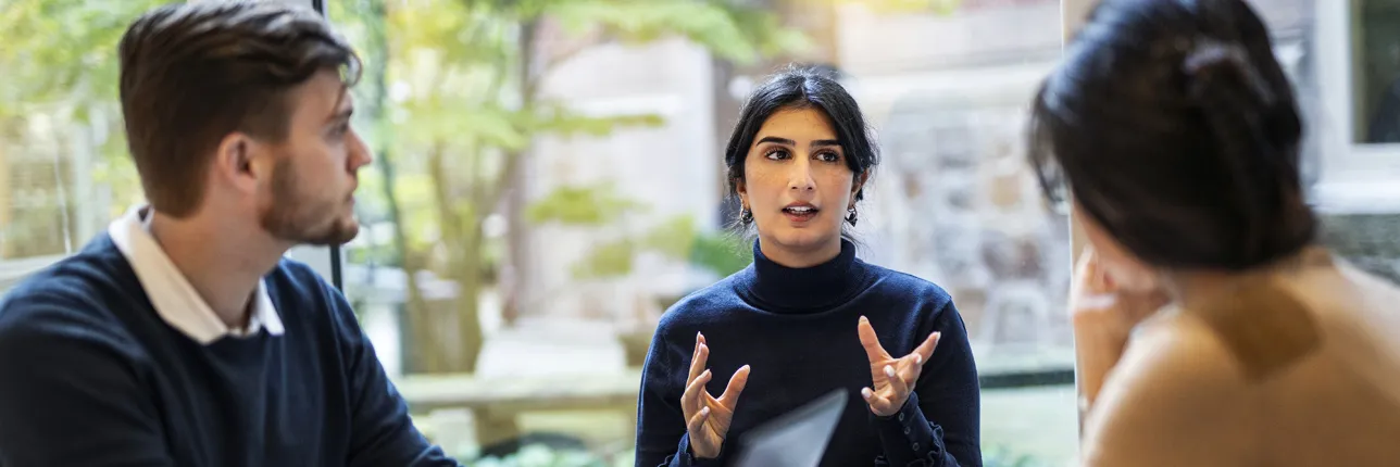 A person gestures while explaining something to two others. Photo: Johan Persson.