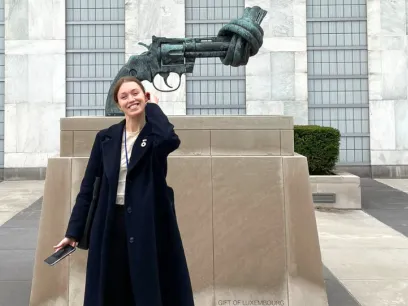 Woman standing in front of of a non violence art piece. Photo