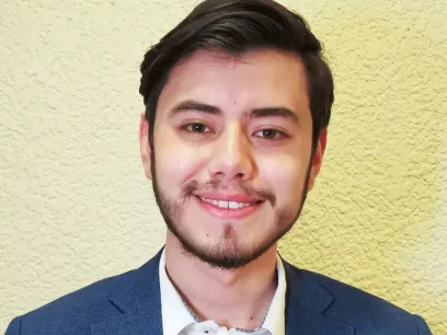 Portrait photo of a smiling male towards a light background.