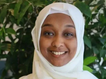 Portrait photo of woman standing with green background.
