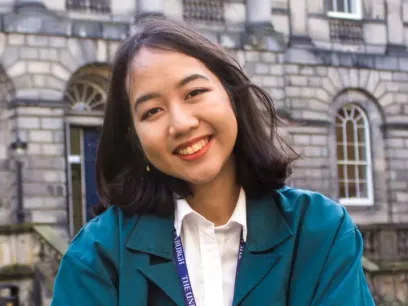Portrait photo of a girl with a stone building behind.