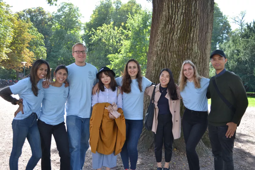 International mentors posing with newly arrived international students under a tree on Arrival Day