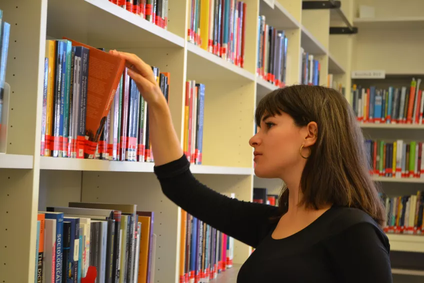 A student taking a book from a shelf at one of the university's libraries