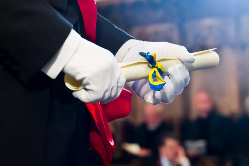 Hands in gloves holding a diploma with ribbons