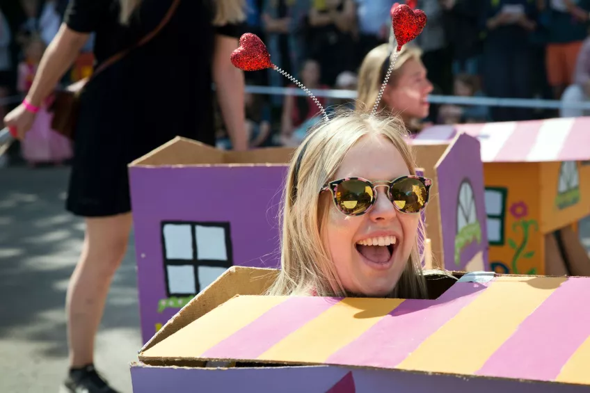 A smiling girl wearing sunglasses and a box in the carnival procession