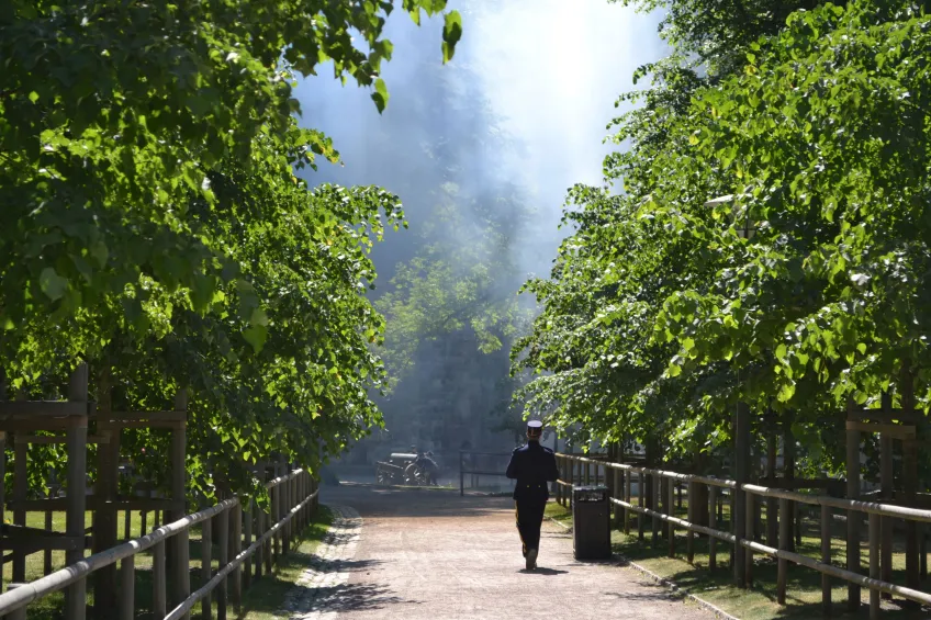 Someone in regimentals walking towards the cannon