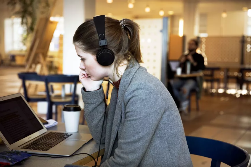 A student with headphones looking at a laptop at Campus Helsingborg