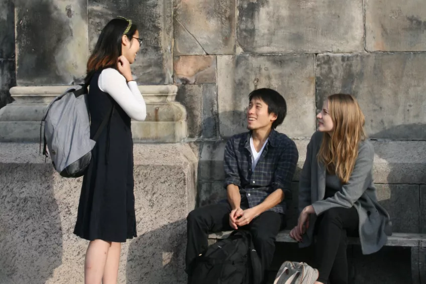 Three students talking at the benches on the side of the cathedral