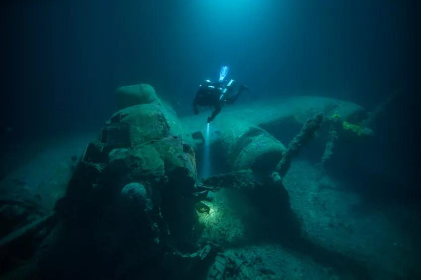 Diver at plane wreck at the bottom of the ocean