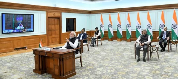 Indias leader Modi at a desk, with many flags behind him
