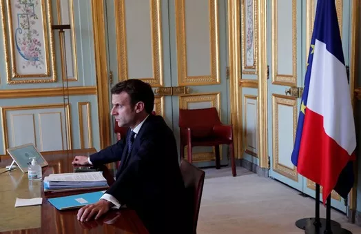 Emmanuel Macron in the Élysée Palace at a desk with hand sanitizer