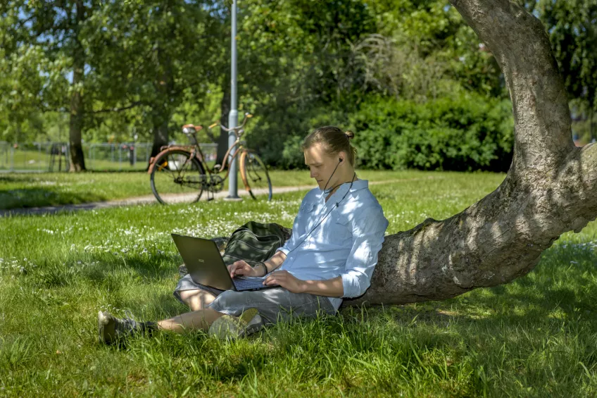 Student studying against a tree. Photo: Kennet Ruona.