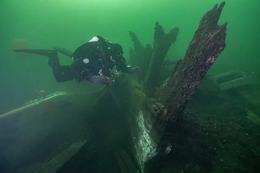 Diver diving by shipwreck