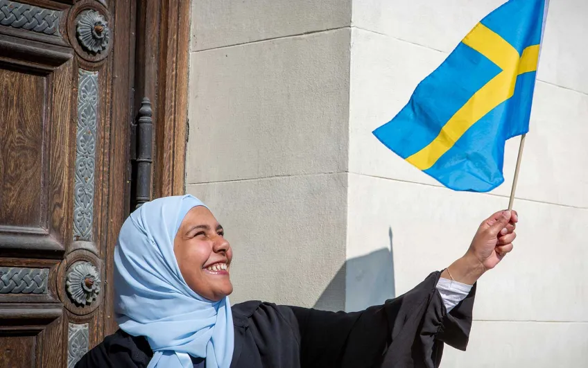 A student waving the Swedish flag. Photo.
