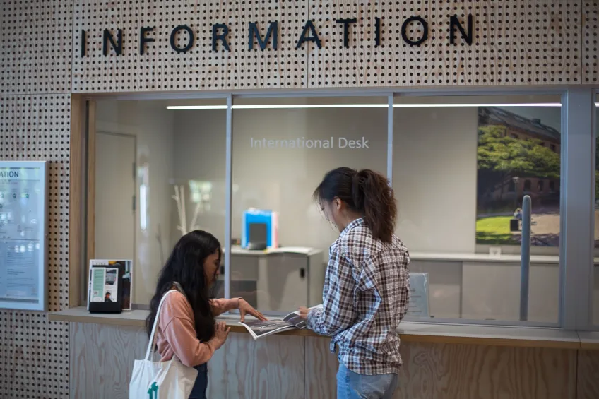 International Desk and two students. Photo.